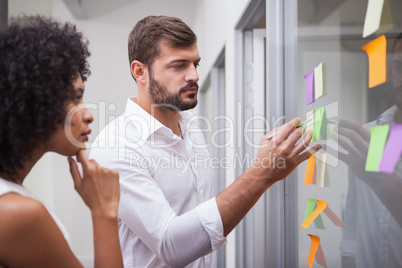 Casual business team looking at sticky notes Casual business team looking at sticky notes