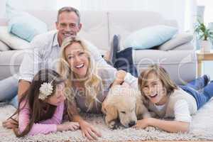 Laughting family with their pet yellow labrador on the rug