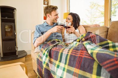 Happy young couple relaxing on the couch with red wine