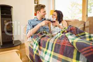 Happy young couple relaxing on the couch with red wine