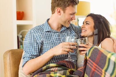 Happy young couple relaxing on the couch with red wine