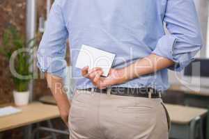Man holding blank business card behind his back