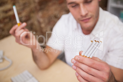 Man deciding between electronic or normal cigarettes
