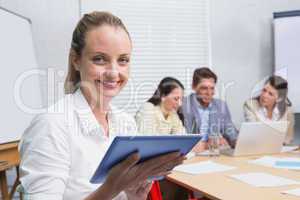 Businesswoman smiling at camera with team behind her