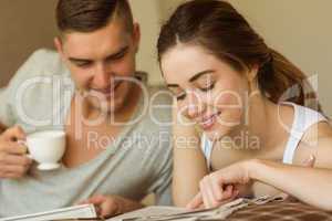 Cute couple reading newspaper in bed