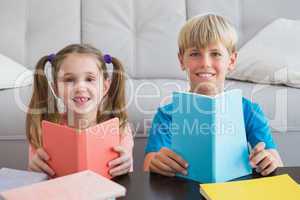 Happy siblings reading books on floor