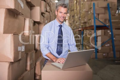 Portrait of warehouse manager using laptop