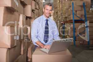 Portrait of warehouse manager using laptop