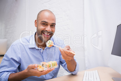 Businessman eating sushi at office desk