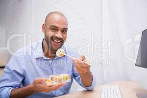 Businessman eating sushi at office desk