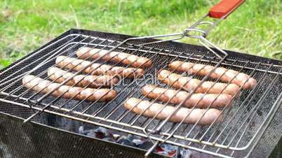 Bratwurst sausages cooking on a wood barbecue.