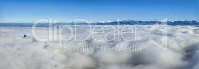 Hot air balloon upon clouds seeing Alps mountains range, Switzerland