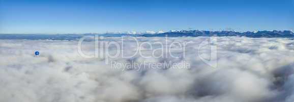 Hot air balloon upon clouds seeing Alps mountains range, Switzerland