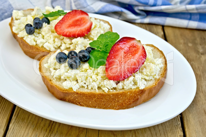 Bread with curd and berries in plate on board