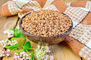 Buckwheat in bowl with flower and napkin on board