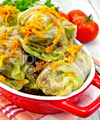 Cabbage stuffed and carrots in red pan on board