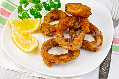 Calamari fried with lemon and fork on plate