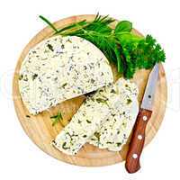 Cheese homemade with knife and herbs on round board
