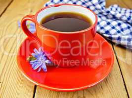 Chicory drink in red cup with napkin and flower on board