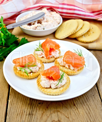 Crackers with cream and salmon in plate on board