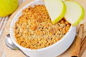 Crumble with pears in bowl on linen tablecloth and board
