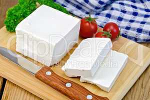 Feta with tomato and knife on wooden board