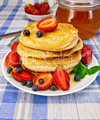 Flapjacks with strawberries and blueberries on blue tablecloth