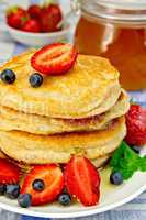 Flapjacks with strawberries and blueberries on linen tablecloth