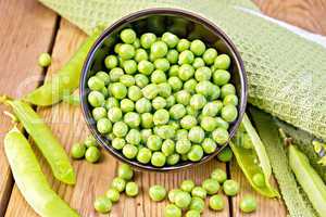 Green peas in brown bowl with napkin on board