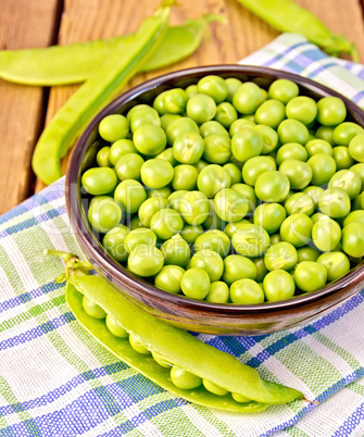 Green peas in brown bowl on checkered napkin