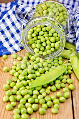 Green peas in glass jar with cloth on board