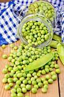 Green peas in glass jar with cloth on board