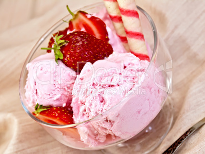 Ice cream strawberry in glass bowl with waffles on fabric