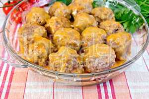 Meatballs with sauce in glass pan on linen tablecloth