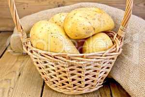Potatoes yellow in basket with burlap on board