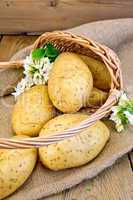 Potatoes yellow in basket with flower on sackcloth and board