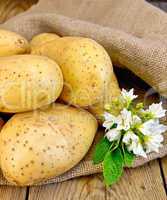 Potatoes yellow with flower on sackcloth and board