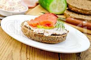 Sandwich with cream and salmon in oval plate on board