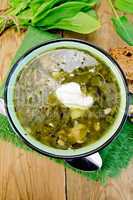Soup green of sorrel and spinach with sour cream on board