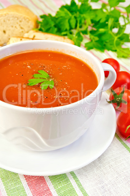 Soup tomato in bowl with tomatoes on linen napkin