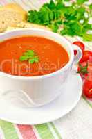 Soup tomato in bowl with tomatoes on linen napkin