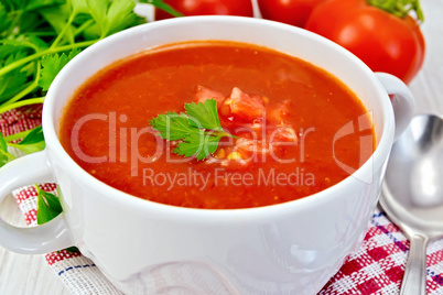 Soup tomato with spoon on napkin and board