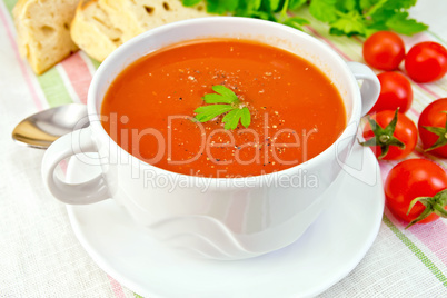 Soup tomato with peppers in bowl on linen napkin