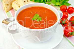 Soup tomato with peppers in bowl on linen napkin