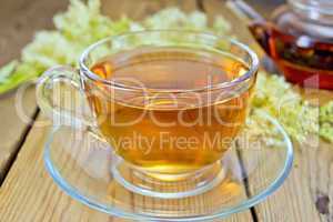 Tea from fresh meadowsweet in glass cup and teapot