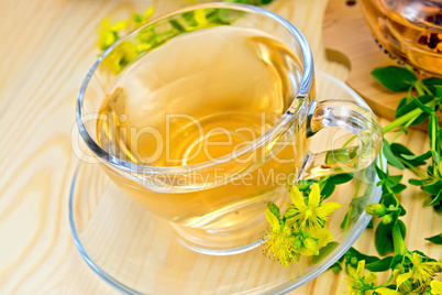 Tea from tutsan in glass cup on board with flowers