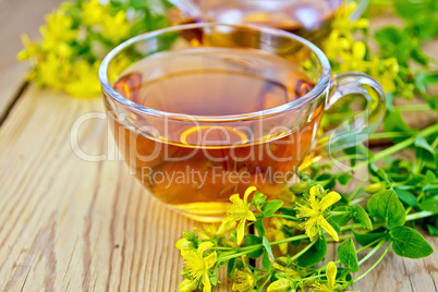 Tea from tutsan in glass cup on board