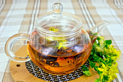 Herbal tea from tutsan in glass teapot on linen tablecloth