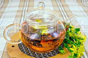 Herbal tea from tutsan in glass teapot on linen tablecloth