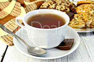 Tea in white cup with different cookies on light board